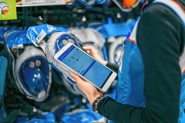 Eien Decathlon-Mitarbeitern checkt Waren auf einem Tablet-Computer.