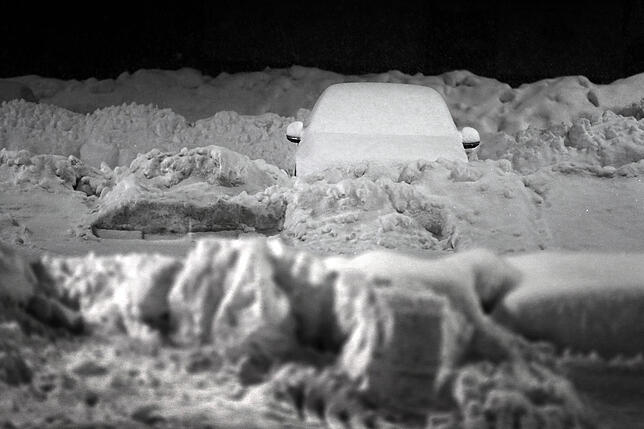 Winter in Bayern Kaufbeuren: Ein schneebedecktes Auto steht auf dem Parkplatz eines Supermarktes.