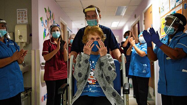 Mitarbeitern des Gesundheitswesens applaudieren den ie90-jährigen Margaret Keenan (Mitte) nach der Impfung.