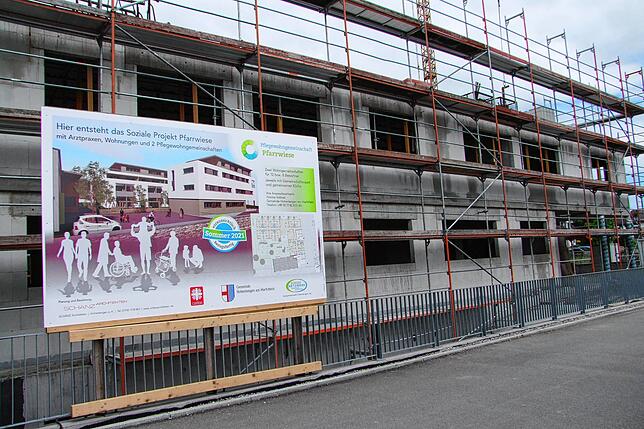 Eine Plakatwand zeigt, wie der Gebäudekomplex des Sozialen Projektes Pfarrwiese einmal aussehen wird.