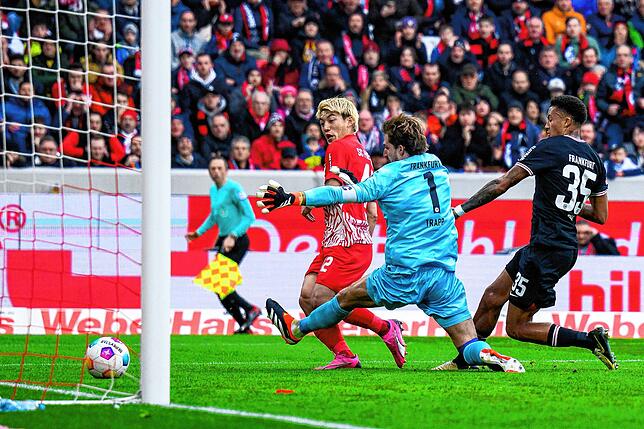Freiburgs Ritsu Doan (l) macht das Tor zum 1:1 gegen Frankfurts Torwart Kevin Trapp (M) und Frankfurts Tuta (r).