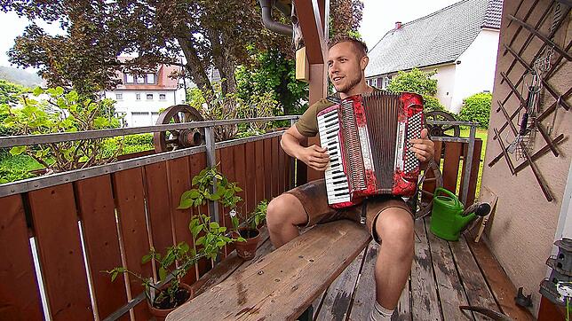 Patrick Romer genießt nach vollbrachtem Tagwerk einen entspannten Moment auf dem Balkon und spielt Akkordeon.