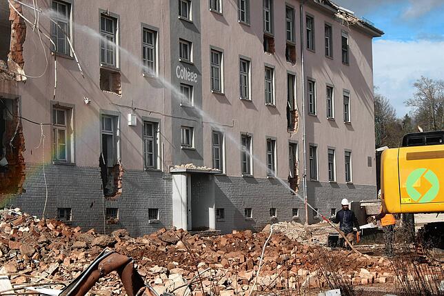 Damit der Staub der Trümmer nicht zu stark umherweht, werden die herabfallenden Brocken mit Wasser besprüht.