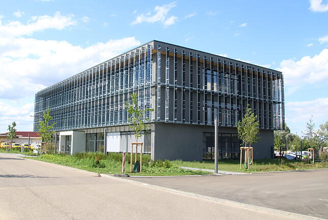 Sogenannte Segel mit Photovoltaik-Ausstattung zieren die Fassade des grauen Betongebäudes. Sie sollen dann ihre volle Leistung ...