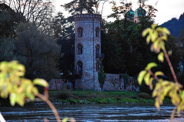 Durch letzte Sonnenstrahlen fällt der Blick von der Fridolinsinsel auf den schlanken Diebsturm im Schlosspark.