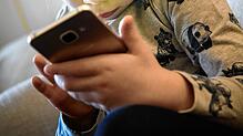 Ein kleines Mädchen ist völlig versunken ins Smartphone.