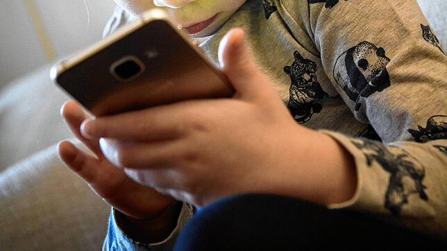 Ein kleines Mädchen ist völlig versunken ins Smartphone.