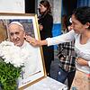 Eine Frau berührt ein Porträt des verstorbenen Papstes Franziskus vor der Pfarrei Caacupe in Buenos Aires, die er oft besuchte und in ...