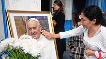 Eine Frau berührt ein Porträt des verstorbenen Papstes Franziskus vor der Pfarrei Caacupe in Buenos Aires, die er oft besuchte und in ...