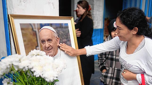 Eine Frau berührt ein Porträt des verstorbenen Papstes Franziskus vor der Pfarrei Caacupe in Buenos Aires, die er oft besuchte und in ...