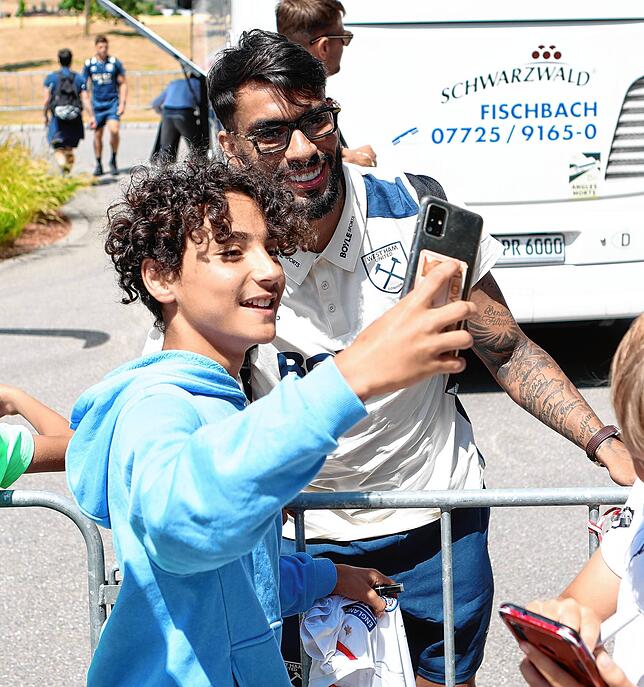 Ein kleiner Fan schießt ein Foto mit Lucas Paqueta.