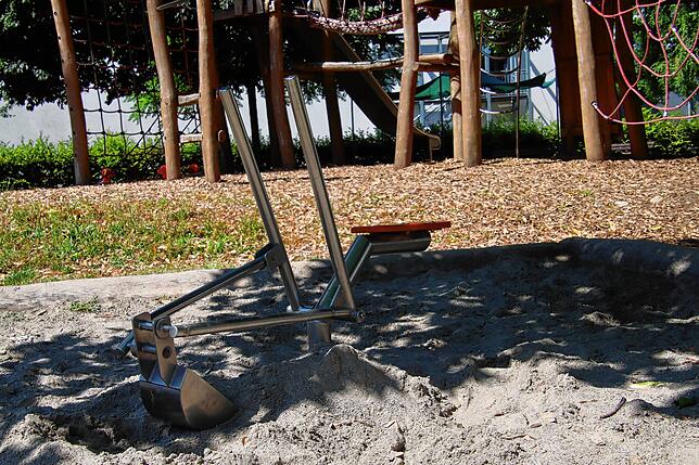 Im Sandkasten ist ein Bagger fest installiert.