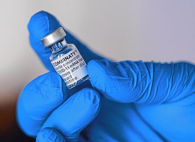 Ein Impfarzt hält bei einem Testlauf den Impfstoff Comirnaty gegen Corona von Biontech/Pfizer in einer Hand.