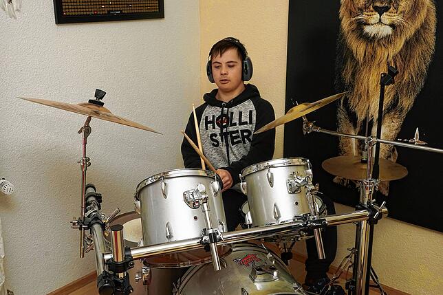 Leon zeigt, wie er die Drumsticks am Schlagzeug schwingt.