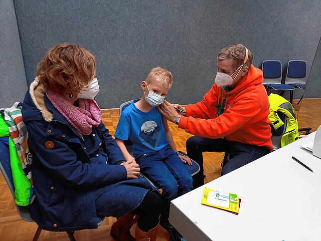 Jakob Schulze aus Jestetten bekommt im Mini-Kiz in Lauchringen von dem pensionierten Arzt Elmar Vehr aus Weilheim die erste Impfdosis ...