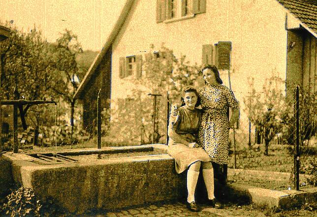 Dora Wunderle (sitzend), das einzige Kind der Familie, mit ihrer Freundin Agnes am Brunnen vor Sigmund Wunderles Haus. Agnes heiratete ...