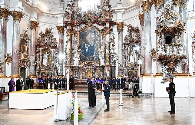 Angehörige der Rettungsdienste legen beim Trauergottesdienst Blumen nieder.