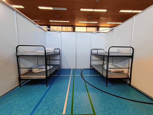 In solche Boxen sind die einzelnen Räume in der Notunterkunft unterteilt. Die Decke ist nach oben zur Halle hin geöffnet.