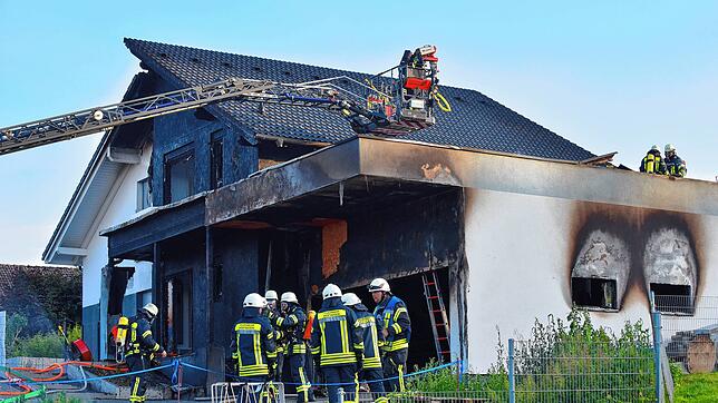 Feuerwehrleute stehen vor der Brandstelle.