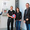 Zeigen den neuen Laien-Defibrillator im Durchgang zum Parkplatz am Dorfgemeinschaftshaus Orsingen (von links): Johanna Ziegler (Björn ...