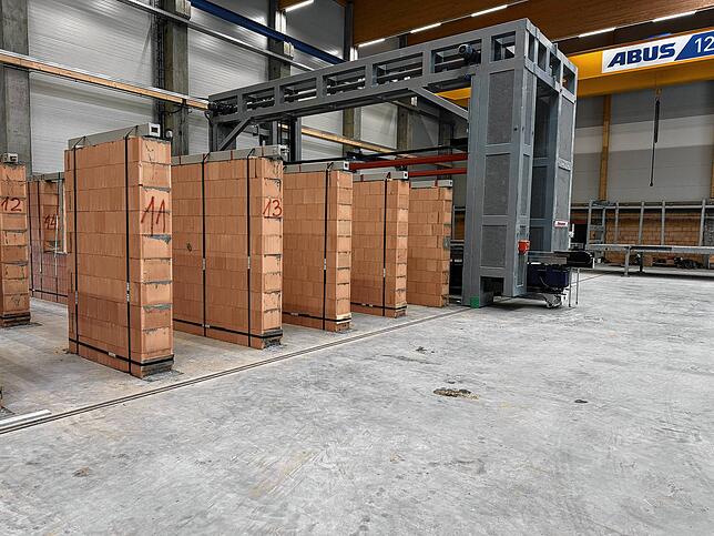 Diese Module sind bereit für die Baustelle und werden noch heute verladen. Im Hintergrund die rückenschonende Wandherstellungsmaschine