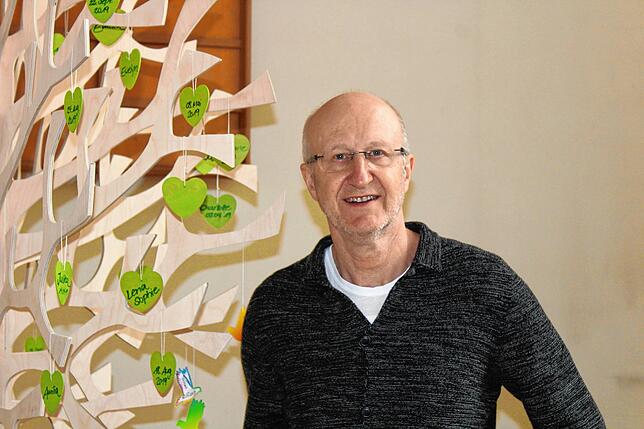 Pfarrer Rainer Stockburger neben dem Taufbaum. Hier hängen die Namen aller Kinder, die in den letzten Monaten getauft wurden.