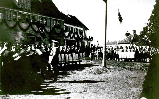 Ein Festakt auf der Ergat, vermutlich nach Kriegsbeginn, da vor allem junge Frauen auf dem Bild zu sehen sind. Der beleibte Mann in ...