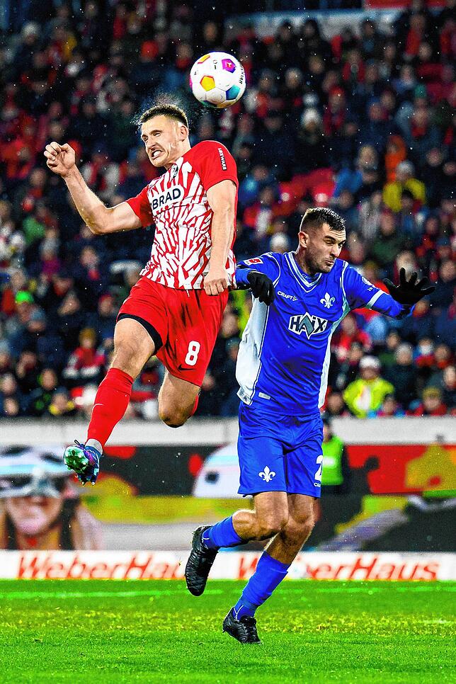 Freiburgs Maximilian Eggestein (l) in Aktion gegen Darmstadts Bartol Franjic (r).
