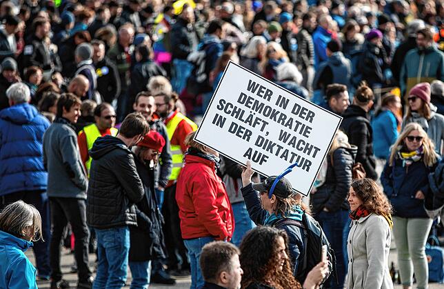 Ein Mann trägt auf einer Demonstration der Initiative “Querdenken„ auf dem Cannstatter Wasen ein Schild mit der Aufschrift ...