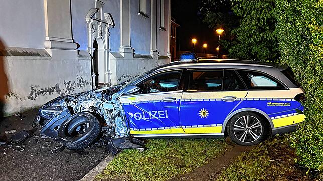 Ein Streifenwagen der Polizei steht schwer beschädigt im Scheinwerferlicht der Feuerwehr an der Kirche in der Ruhe-Christi-Straße in ...