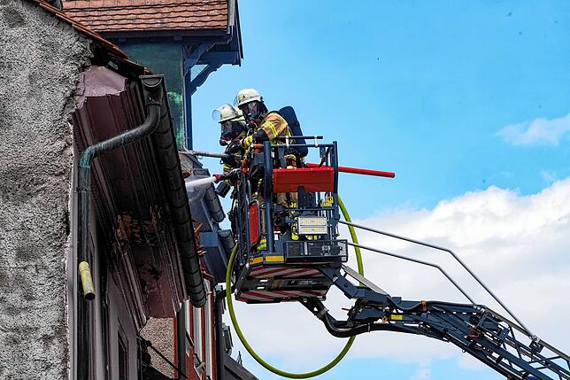 Auf der Drehleiter inspizieren die Feuerwehrleute am Tag nach dem verheerenden Brand eines der Dächer.