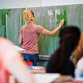 Eine junge Lehrerin an der Tafel im Mathematikunterricht einer achten Klasse.