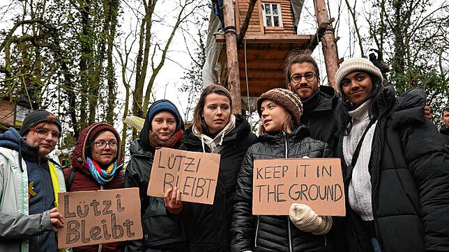 Luisa Neubauer (mit &bdquo;Lützi bleibt&ldquo;-Schild) und Greta Thunberg (rechts daneben) beim Protest in Lützerath.
