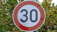Ein Schild in einer Ortsdurchfahrt schreibt aus Lärmschutzgründen Tempo 30 vor.
