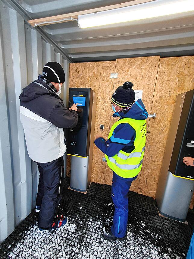 Siegfried Zettler erklärt einem Skifahrer wie er sein Ticket lösen kann.