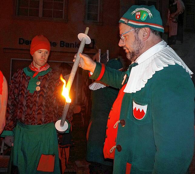 Letzte Vorbereitungen: Ein Zunftrat holt sich bei einer Schlosshexe Feuer, gleich geht es im Schein von vielen Fackeln beim Wecken durch ...