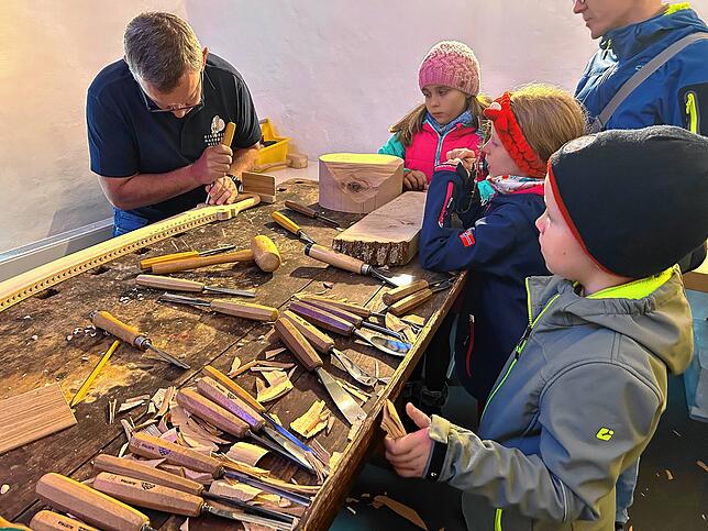 Dem Säbelschnitzer über die Schulter schauen: Die Kinder staunen, wie Peter Hupfer den Narrosäbel schnitzt.