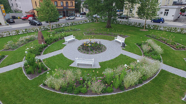 Ein Rondell in einem der Quader wurde mit Sitzgelegenheiten und Blumenflächen gestaltet. Dort ist auch ein Obelisk mit einem Bildnis von ...