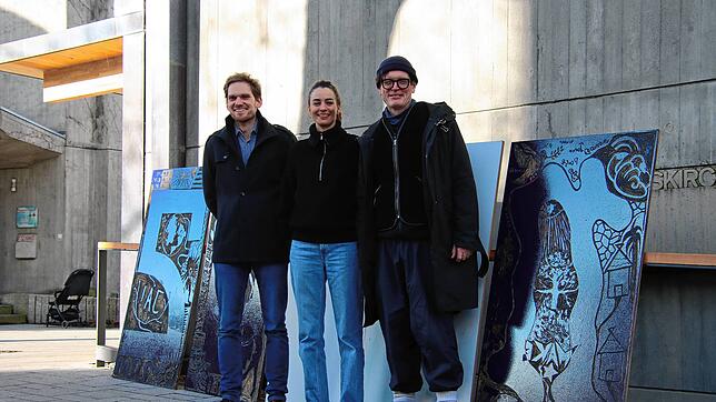 Pfarrer Alexander Philipp sowie Ana Baumgart und Daniel Franz (beide FKZ) stehen neben den Druckplatten des Kunstwerks vor der ...