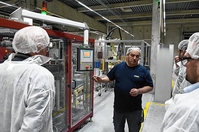 Fertigungsleiter Vincenzo Ferraina erklärt der Besuchergruppe eine der Maschinen in der Produktion.