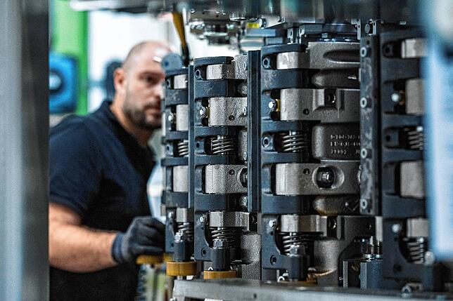 Ein Mitarbeiter einer Maschinenbaufirma arbeitet in der Produktion an einer Streckblasmaschine. Bekommt man das Fachkräfteproblem in den ...
