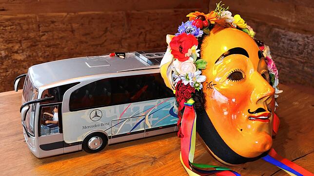 Eine Eschinger Hanselmaske lehnt am Modell eines Reisebusses. Diese Kombination thematisiert das Ungemach, das vielen Narren in der ...