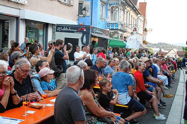 Dicht gedrängt sitzen die Besucher auf den Bänken vor der Bühne. Dort ird gesungen, musiziert und getanzt.