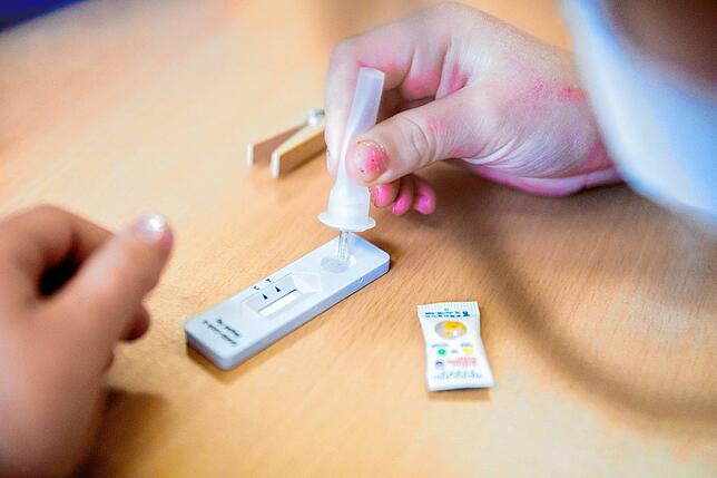 Eine Schülerin trägt bei einem Probelauf mit Corona-Schnelltests an einer Berliner Grundschule die Trägerflüssigkeit auf einen ...