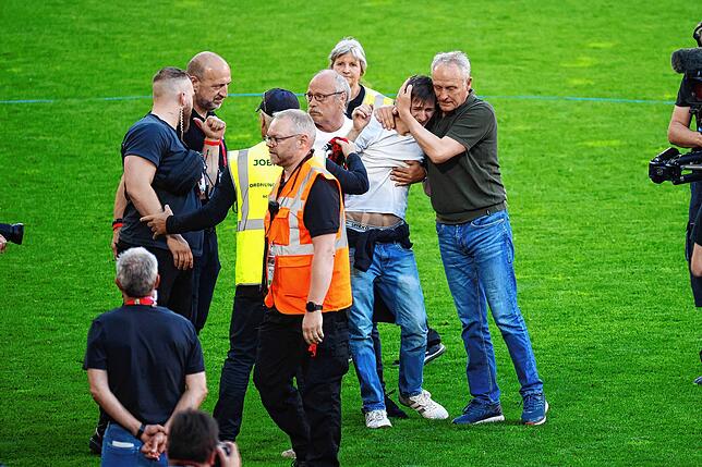 Ein Fan auf dem Rasen: Christian Streich entschärft die Situation per Umarmung.