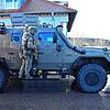 Ein Beamter des Spezialeinsatzkommandos (SEK) ist hinter einem gepanzerten Polizeiwagen gedeckt.