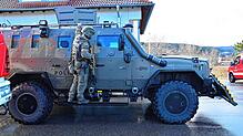 Ein Beamter des Spezialeinsatzkommandos (SEK) ist hinter einem gepanzerten Polizeiwagen gedeckt.