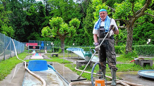 Bernhard Kreutter befreit die blauen Bahnen im hinteren Teil der Minigolfanlage nach dem Hochwasser vom Schlamm.