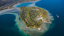 Die Insel Mainau liegt im Sonnenlicht im satt blauen Bodensee.
