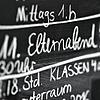 An der Tafel wird der Elternabend angekündigt – bei vielen Eltern nicht gerade ein beliebter Termin.